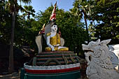 Myanmar - Inwa, white washed stupas with a Buddha statue protected by a naga where the road branch off to the teack monastery.